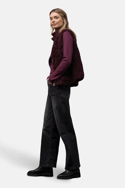 Gilet bordeaux en fourrure synthétique de Street One, porté sur un pull à col roulé et un jean noir.