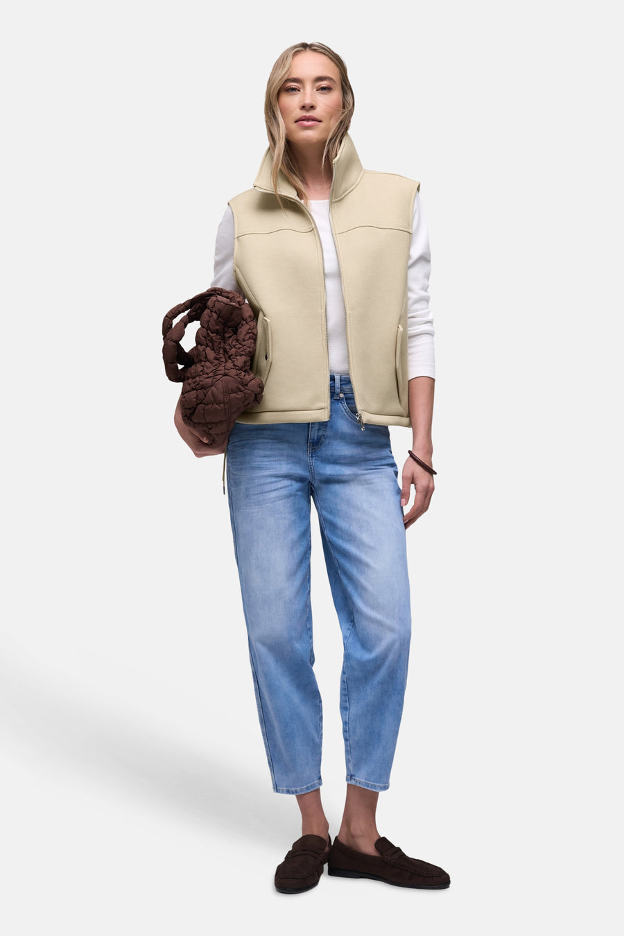 Gilet beige de STREET ONE, porté sur un t-shirt blanc à manches longues et un jean bleu clair, avec sac marron.
