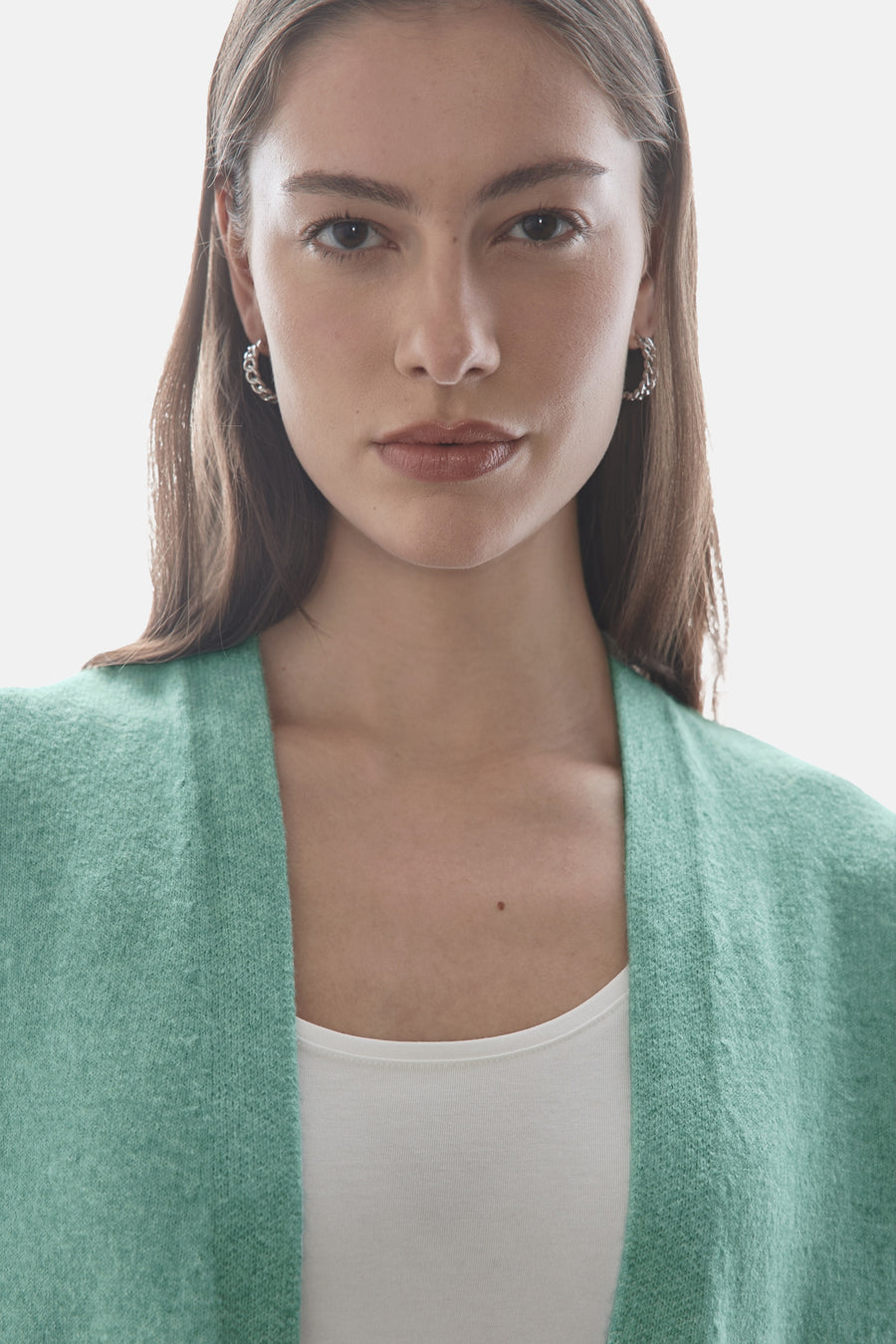 Groene cardigan van Street One, open gedragen over een witte tanktop, met zilveren oorbellen.