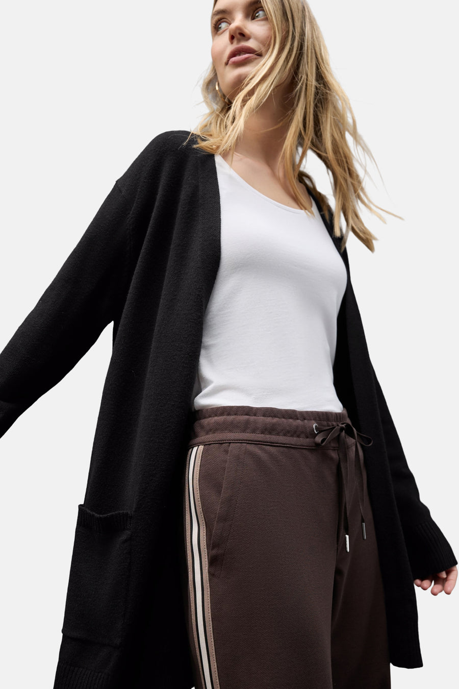 Gilet noir de Street One, porté sur un t-shirt blanc et un pantalon de survêtement marron à rayures.