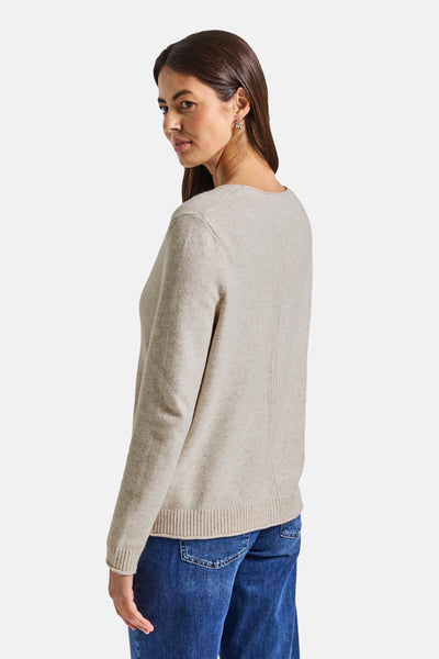 Cardigan beige de Street One, manches longues, détail de couture verticale au dos, porté avec un jean bleu foncé.
