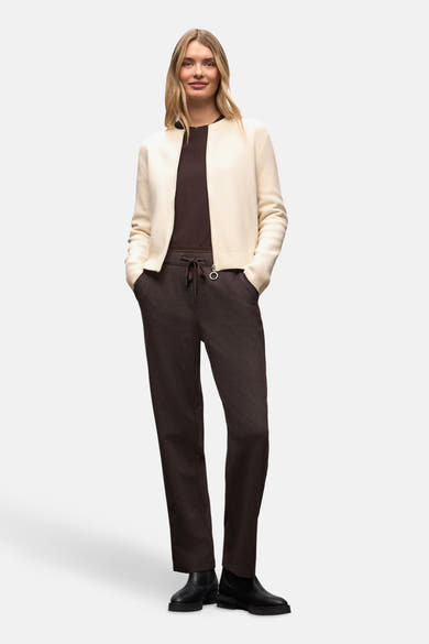Cardigan écru de Street One, porté ouvert sur un t-shirt marron, avec un pantalon marron à cordon et des bottines noires.
