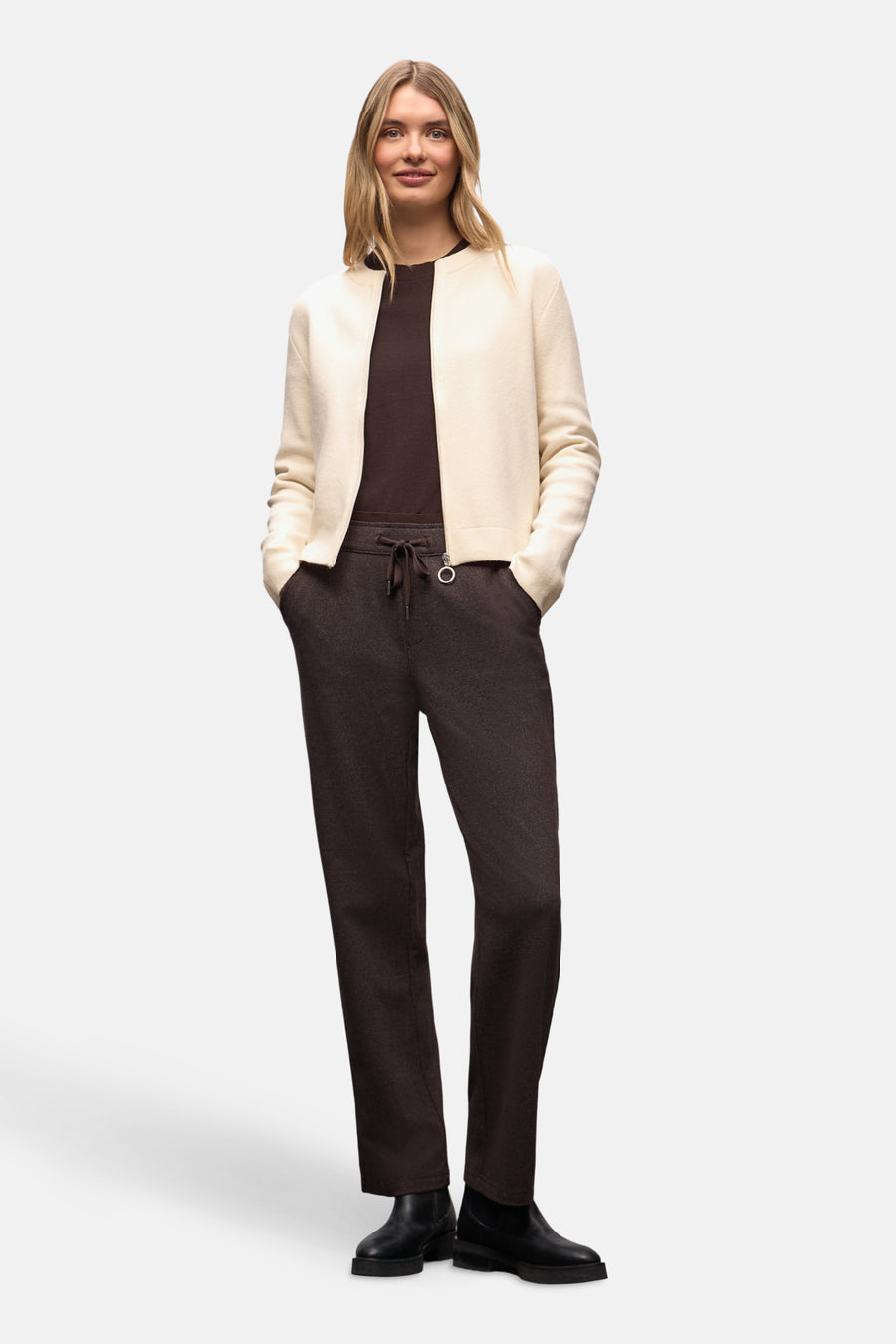 Cardigan écru de Street One, porté ouvert sur un t-shirt marron, avec un pantalon marron à cordon et des bottines noires.
