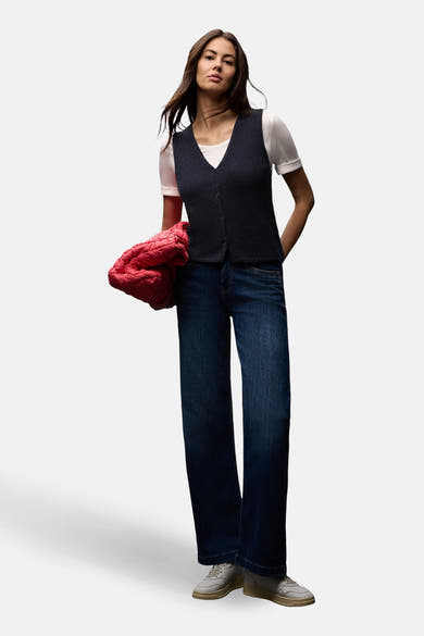 Blauwe tanktop van STREET ONE, gedragen over een wit T-shirt, met een blauwe jeans en een rode jas.