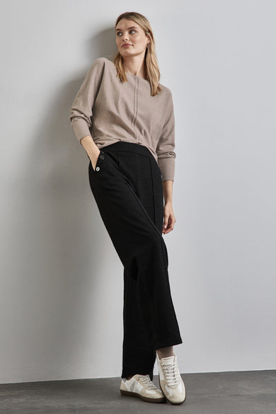 Pull col O beige de STREET ONE, porté avec un pantalon noir à boutons et des chaussures de sport blanches.