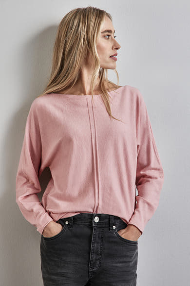Roze trui met ronde hals van STREET ONE, gedragen met een zwarte broek en een geruite jas.