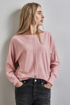 Roze trui met ronde hals van STREET ONE, gedragen met een zwarte broek en een geruite jas.