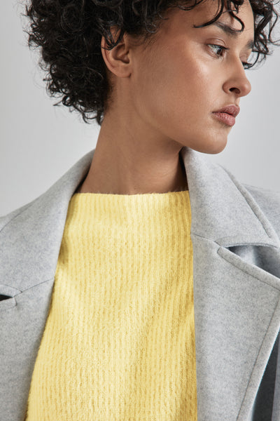 Pull à col rond jaune de Street One, porté avec un manteau gris clair.
