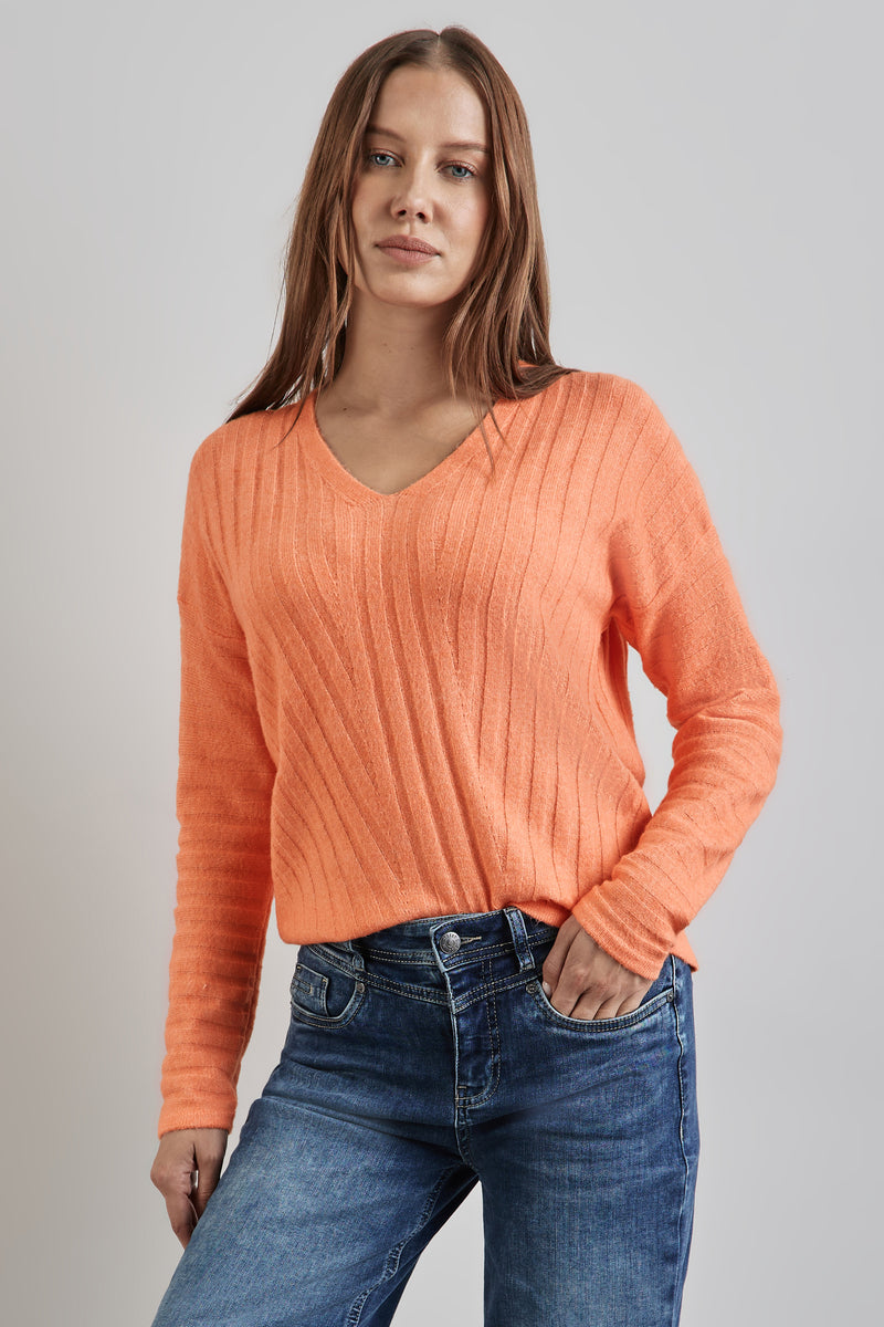 Pull à col en V orange de STREET ONE, à côtes verticales portés avec un jean bleu.
