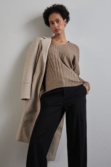 Pull à col en V beige de Street One avec motif côtelé, porté avec un pantalon noir et un manteau.