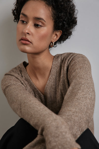 Beige V-hals trui van Street One, gedragen met gouden oorbellen en een zwarte broek.