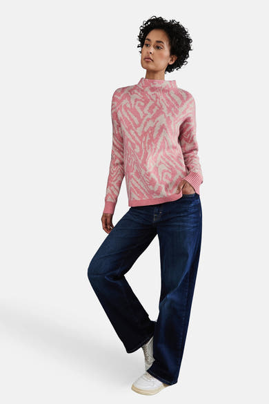 Pull à col roulé corail par Street One, motif zébré porté avec un jean bleu ample et des baskets blanches.

