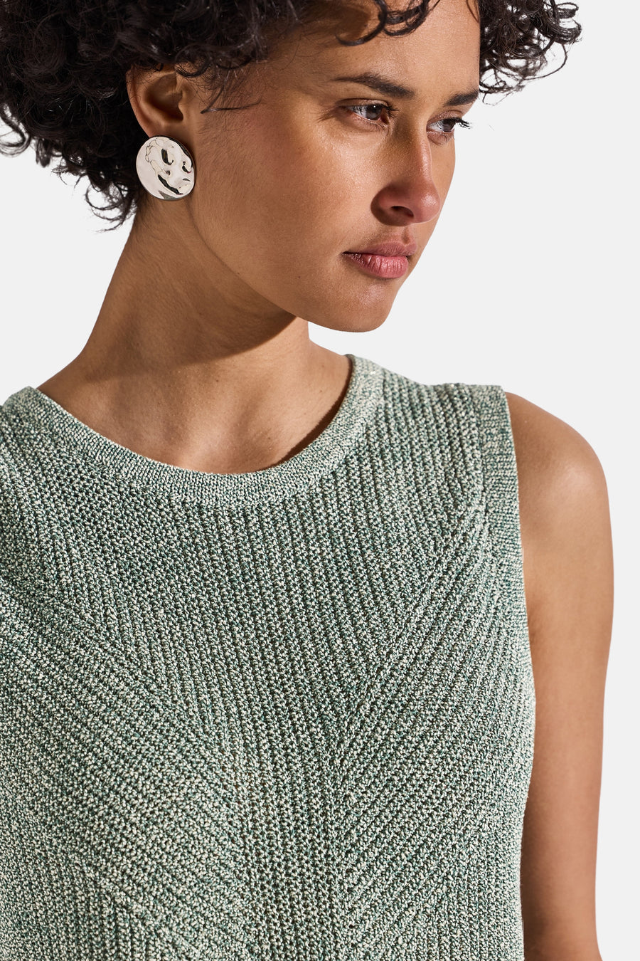 Top sans manches vert de Street One, avec un motif à chevrons tricoté et des boucles d'oreilles rondes brillantes.
