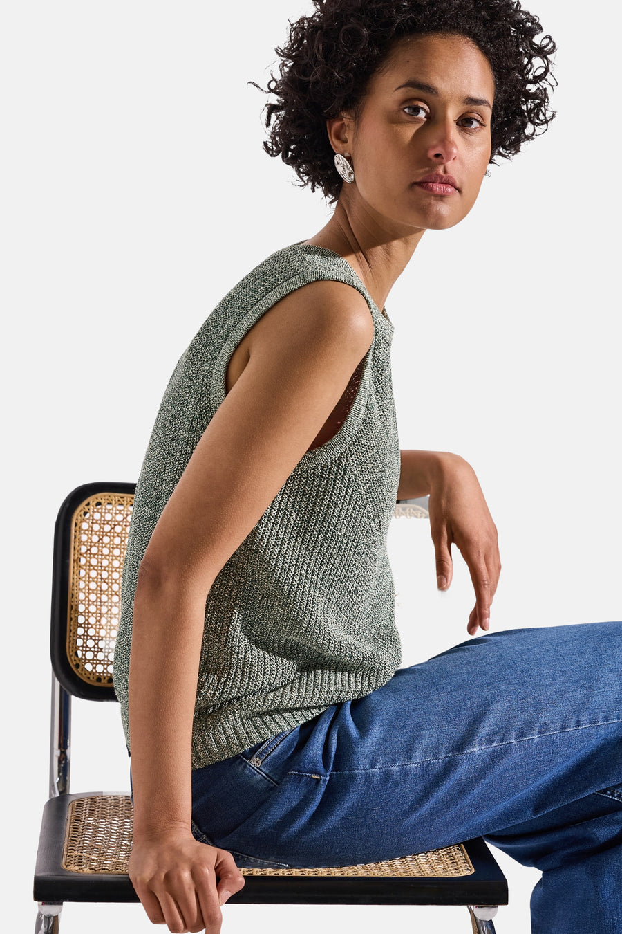 Top sans manches vert de Street One, porté avec un jean, sur une chaise en osier.