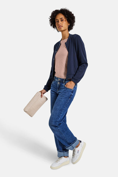 Roze rondehals trui van Street One, gedragen met een marineblauwe cardigan, een blauwe jeans en een beige tas.