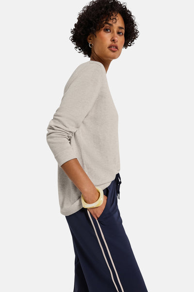 Top uni manches longues beige de STREET ONE, porté avec un pantalon bleu marine à rayures et un bracelet jaune.
