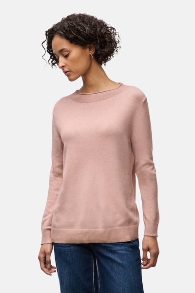 Pull rose en tricot by Street One, porté avec un jean bleu et des boucles d'oreilles rondes.
