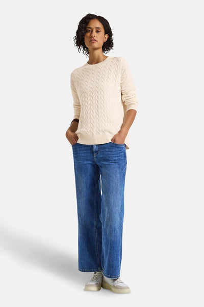 Pull col rond écru de STREET ONE, avec motif à torsades et porté avec un jean large bleu et des baskets blanches.
