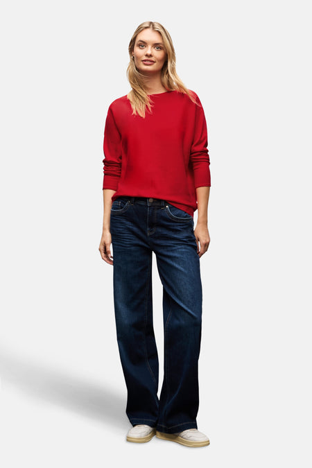Pull à col rond rouge de STREET ONE porté avec un jean ample et des baskets blanches.
