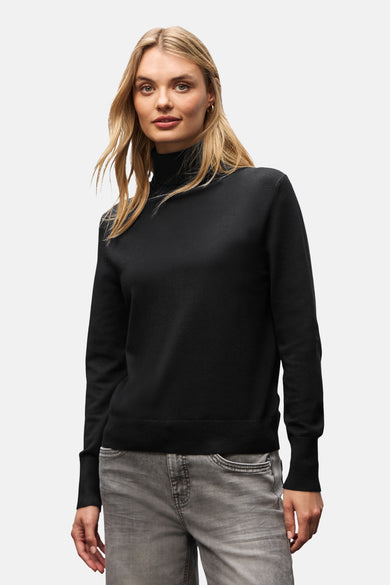 Zwarte coltrui van Street One gedragen met een verbleekte grijze broek en witte sneakers.