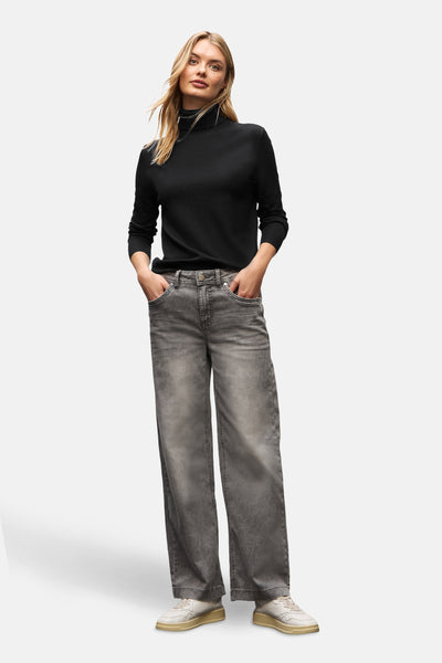 Pull col montant noir de Street One porté avec un pantalon gris délavé et des baskets blanches.