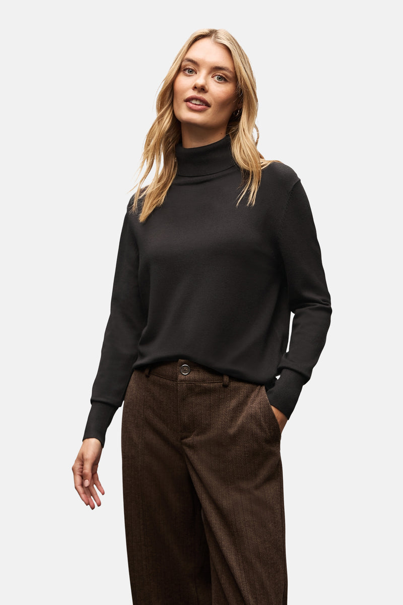 Pull col montant noir de Street One, porté avec un pantalon à chevrons marron.