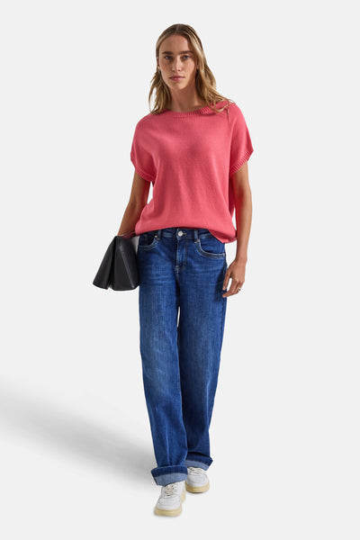 Ronde hals trui koraal van Street One met blauwe jeans en zwarte clutch.