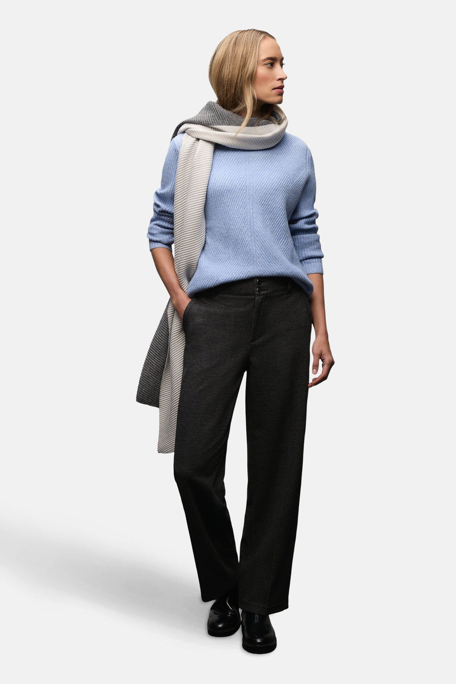 Pull col montant bleu par STREET ONE, porté avec un pantalon anthracite et une écharpe à rayures.