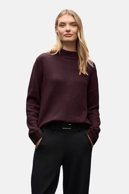 Ronde hals trui bordeaux van STREET ONE, gedragen met een zwarte broek en een bruine suède tas.