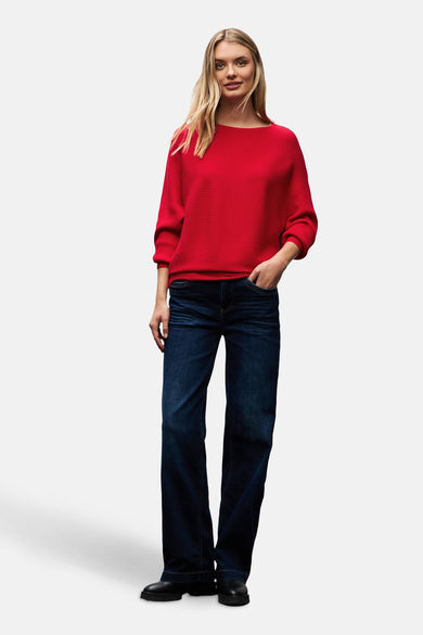 Pull col rond rouge de STREET ONE, porté avec un jean ample bleu foncé et des chaussures noires épaisses.