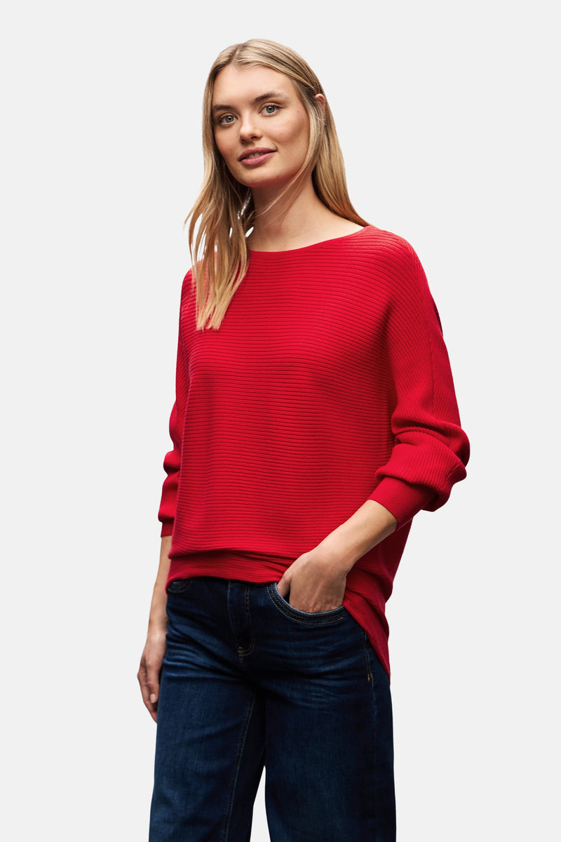 Pull col rond rouge de STREET ONE, porté avec un jean bleu foncé et les cheveux blonds lâchés.
