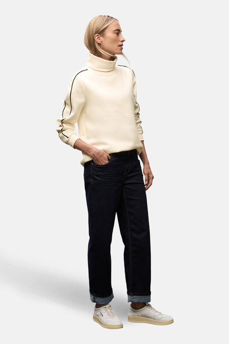 Ecru coltrui van STREET ONE, met zwarte strepen op de mouwen, gedragen met een donkerblauwe jeans en witte sneakers.