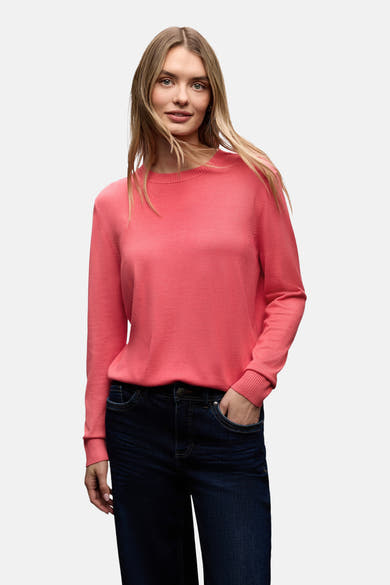 Ronde hals trui koraal van STREET ONE, gedragen met een donkere high-waist jeans en zwarte enkellaarsjes.