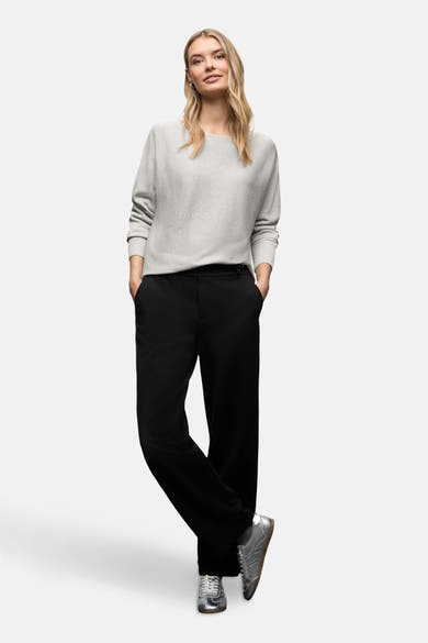 Top uni manches longues argenté de Street One porté avec un pantalon noir et des baskets argentées.