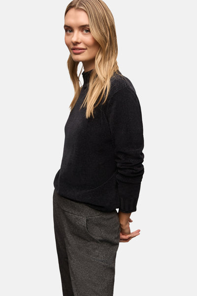Pull col montant noir de Street One, porté avec un pantalon gris à motifs chinés.
