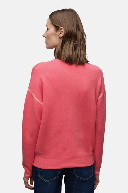 Pull col rond corail de STREET ONE avec manches longues et finitions rayées, porté avec un jean bleu.
