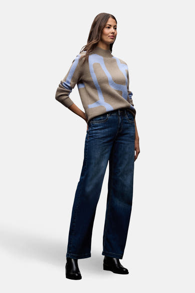 Pull col montant multicolore de Street One, porté avec un jean bleu foncé et des bottines noires.

