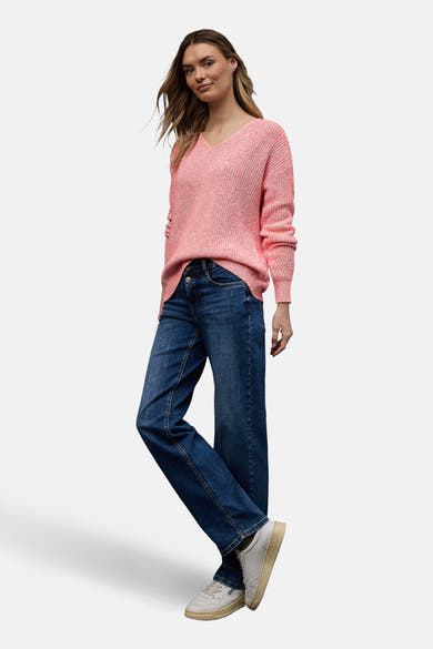 Pull à col en V corail de Street One, en tricot texturé, porté avec un jean bleu foncé et des baskets blanches.
