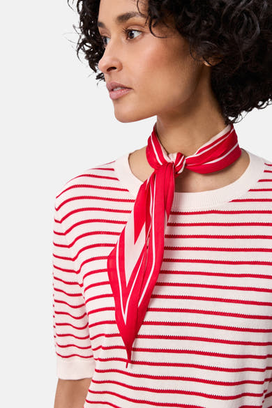 Pull multicolore à col rond de Street One, avec motif rayé rouge et blanc, porté avec un foulard rouge.