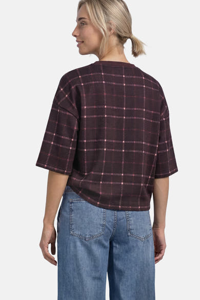 Multicolored checkered O-neck sweatshirt with short sleeves, worn by model in side view with blue jeans