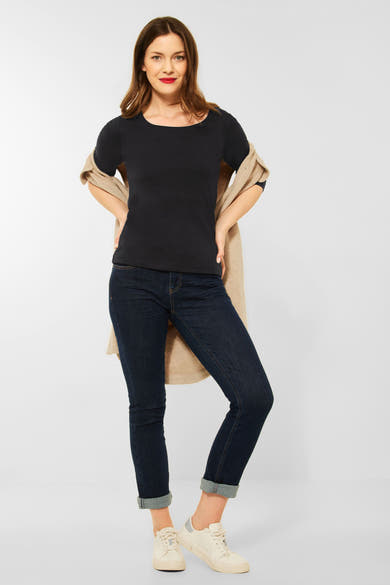 T-shirt noir par STREET ONE, porté avec un cardigan beige sur les épaules et un jean foncé retroussé.