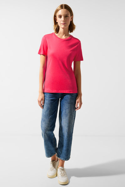 Koraalkleurig T-shirt met korte mouwen van Street One, gedragen met een blauwe jeans en witte sneakers.