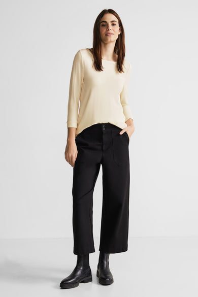T-shirt beige de Street One, manches trois quarts, porté avec un pantalon noir large et des bottines en cuir noir.
