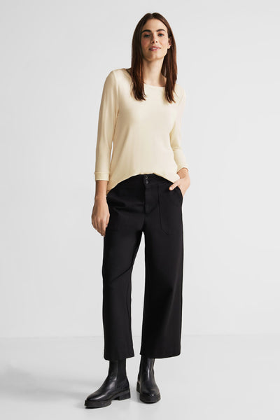 T-shirt beige de Street One, manches trois quarts, porté avec un pantalon noir large et des bottines en cuir noir.
