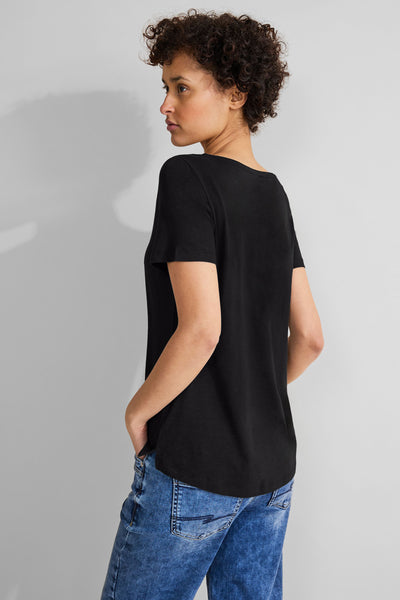 T-shirt noir de STREET ONE, manches courtes, porté avec un jean bleu, vue de dos, femme aux cheveux courts et bouclés.