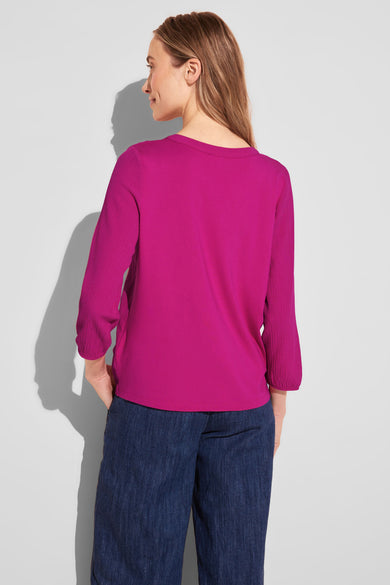 T-shirt rose de STREET ONE, manches longues texturées, porté avec un pantalon ample en denim.
