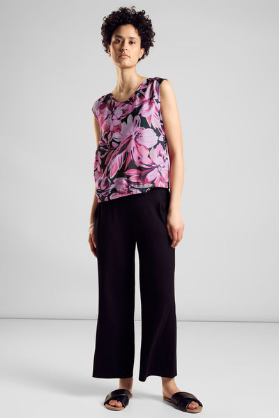 Top sans manches rose de STREET ONE avec un motif floral, porté avec un pantalon noir ample et des sandales.
