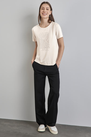 Top uni manches courtes blanc de STREET ONE, avec un motif graphique, porté avec un pantalon noir et des baskets.