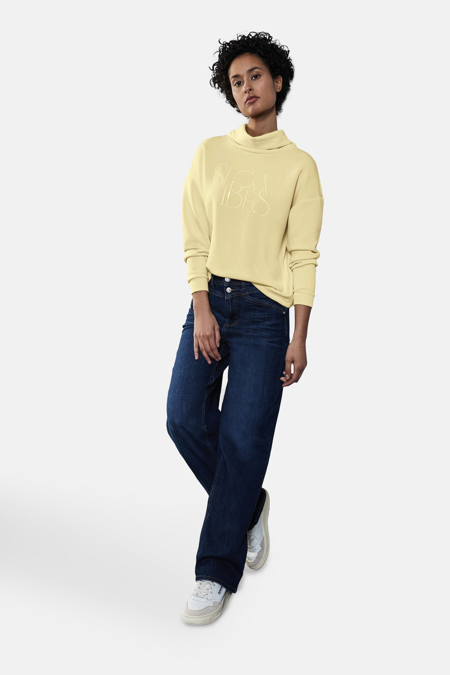 Sweat jaune, de STREET ONE, avec motif texte en relief, porté avec un jean bleu et des baskets blanches.