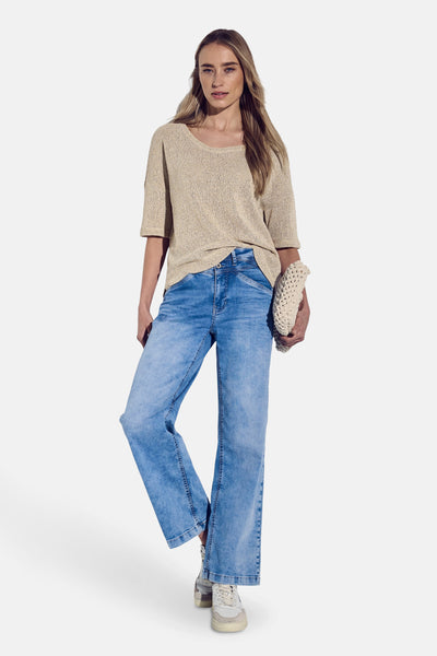 T-shirt à manches courtes beige de Street One, avec une texture tricotée et porté avec un jean bleu et des baskets.

